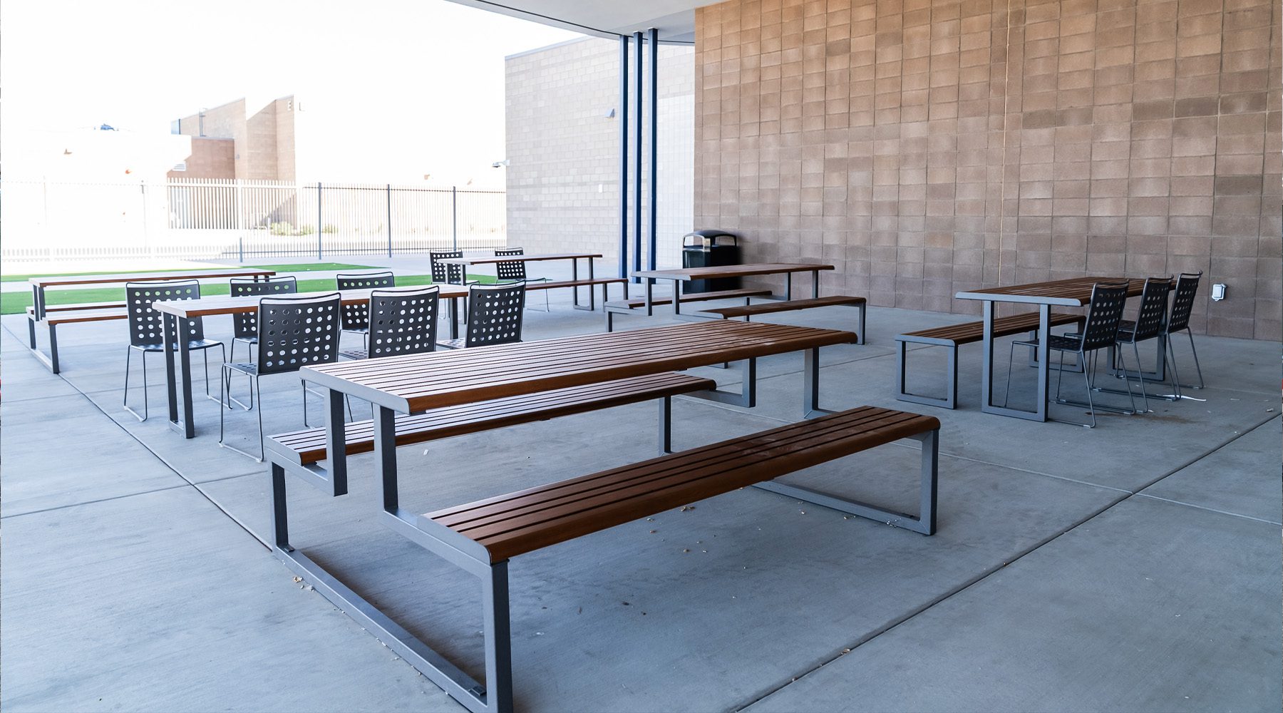 Outdoor student seating area with durable tables and benches arranged for socializing and collaboration, offering a flexible open-air environment that supports informal learning and connection.