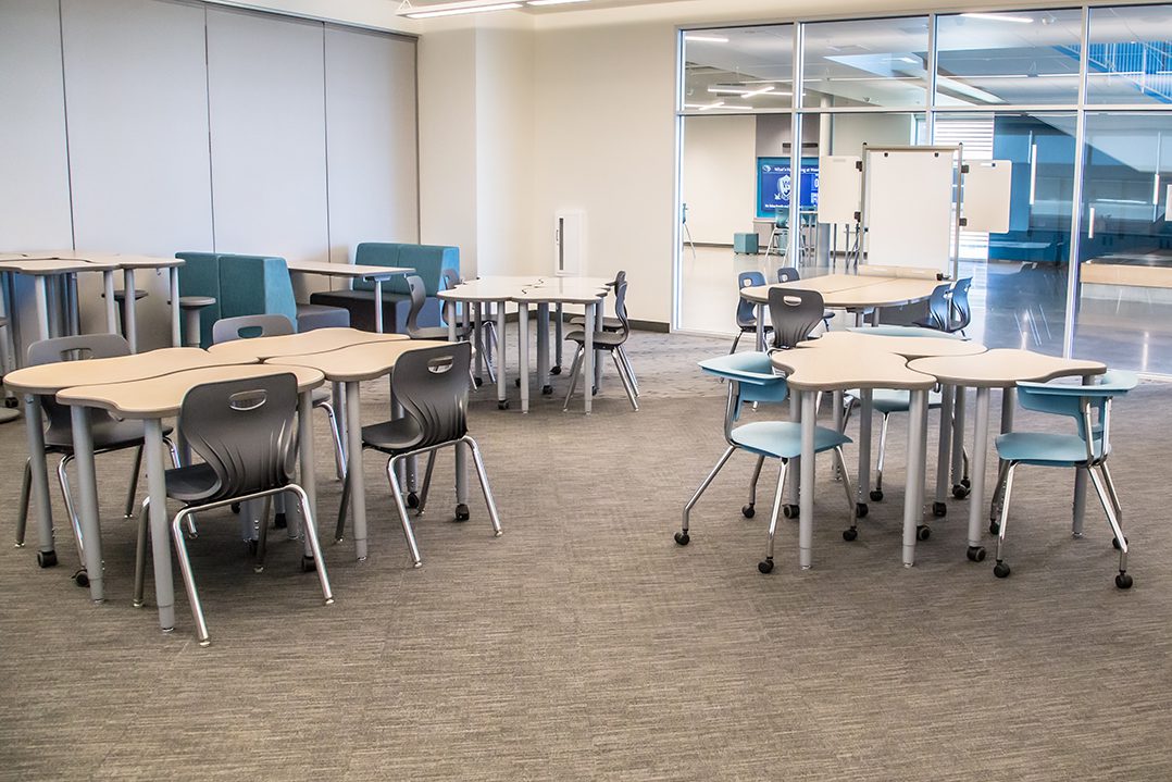 Flexible classroom with modern desks, mixed seating, and writable surfaces in a collaborative layout.